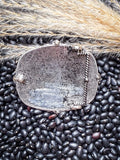 Back of silver Western buckle on black beans and wheat.